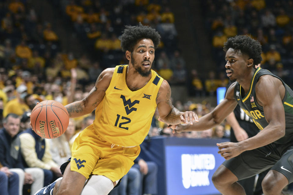 West Virginia guard Taz Sherman (12) protects the ball from Baylor guard Adam Flagler (10) during the first half of an NCAA college basketball game in Morgantown, W.Va., Tuesday, Jan. 18, 2022. (William Wotring)