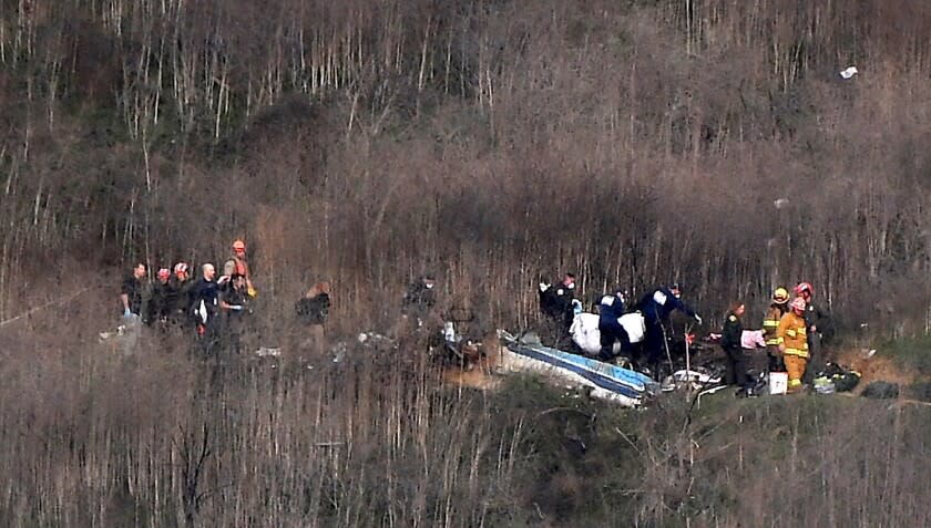 Officials remove a body from the wreckage in Calabasas on Sunday where Kobe Bryant and his daughter Gianna were among 9 dead in a helicopter crash. (Christina House / Los Angeles Times)