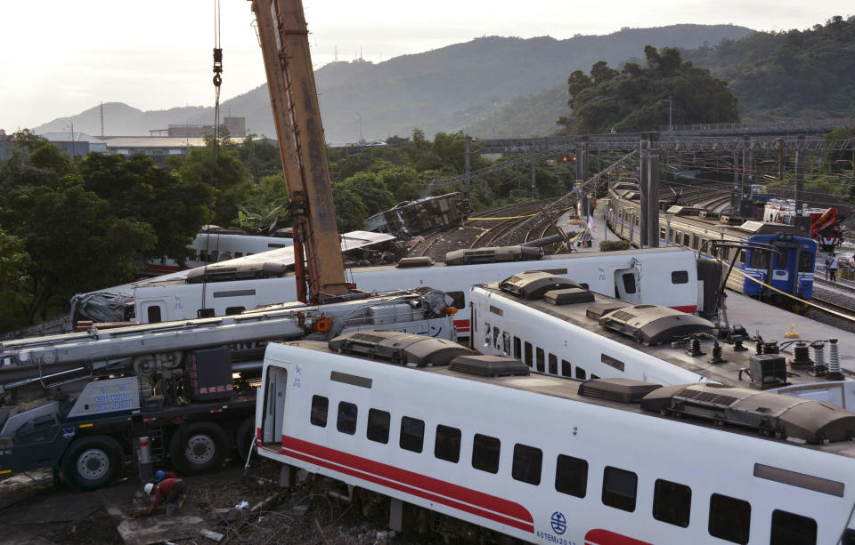 Rescue workers work at the site of a train derailment in Yilan county northeastern Taiwan Monday, Oct. 22, 2018. Passengers were killed and injured on Sunday when one of Taiwan's newer, faster trains derailed on a curve along a popular weekend route, officials said.(Kyodo News via AP)