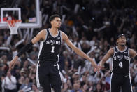 San Antonio Spurs center Victor Wembanyama (1) celebrates a score with guard Devonte' Graham (4) during the second half of an NBA basketball game against the Denver Nuggets in San Antonio, Friday, April 12, 2024. (AP Photo/Eric Gay)