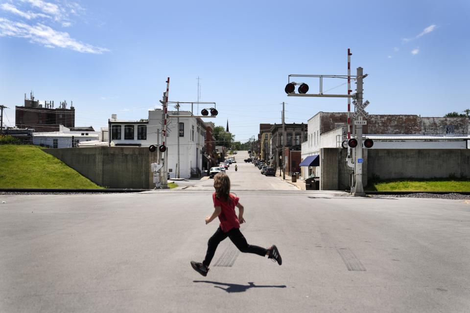 A child runs past an opening in the flood wall protecting downtown Hannibal, Mo., Wednesday, May 22, 2024. The wall protected downtown Hannibal during the flood of 1993 not long after it was completed keeping business open and tourists coming while some homes outside were swamped. (AP Photo/Jeff Roberson)