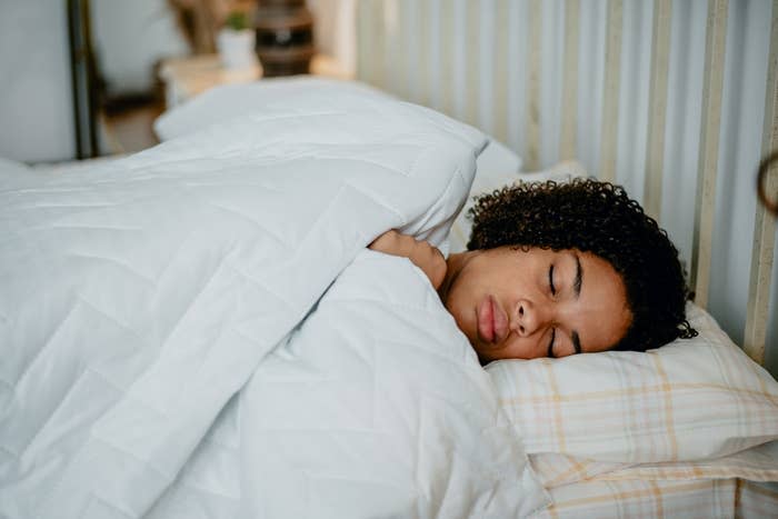 Person sleeping peacefully in bed with white sheets and a cozy comforter