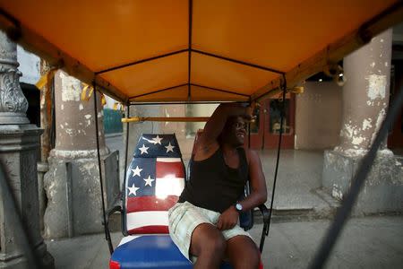 Self-employed pedicab driver Edy Bilbao, 32, talks to friends (not pictured) as he waits for customers in downtown Havana April 12, 2016. REUTERS/Alexandre Meneghini