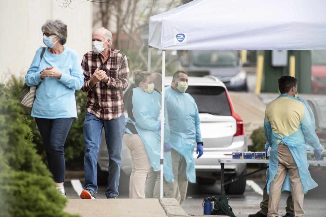 A couple wipes their hands with hand sanitizer as they walk to be screened for the new coronavirus at Huntsville Fever & Flu Clinic on Wednesday, March 18, 2020, in Huntsville, Ala.