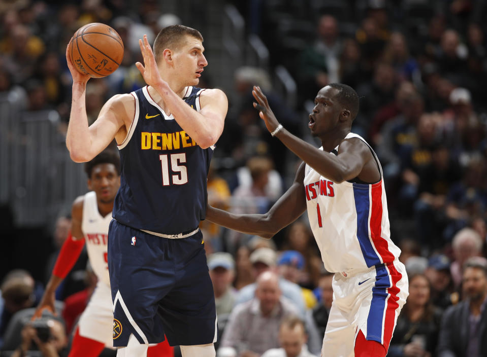 Denver Nuggets center Nikola Jokic, left, looks to pass the ball as Detroit Pistons forward Thon Maker defends in the first half of an NBA basketball game Tuesday, Feb. 25, 2020, in Denver. (AP Photo/David Zalubowski)
