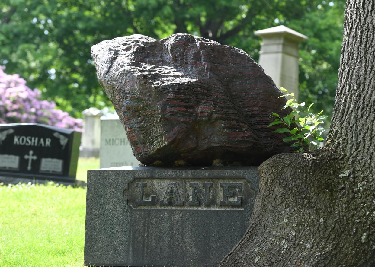 A striped boulder rests atop a granite base marking the graves of Samuel Alanson Lane and his family at Glendale Cemetery in Akron.