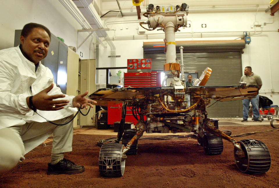 FILE - In this Feb. 4, 2004 file photo, Edward Tunstel Jr., left, a mobility engineer, briefs a reporter about the capability of the Mars rovers Spirit and Opportunity using this full-scale working version, at NASA's Jet Propulsion Laboratory, in Pasadena, Calif. Mars has a nasty habit of living up to its mythological name and besting Earth when it comes to accepting visitors. NASA's InSight is the latest spacecraft to come calling, with every intent of landing and digging deeper into the planet than anything that's come before. The lander arrives at Mars on Monday, Nov. 26 following a six-month journey.(AP Photo/Ric Francis, File)