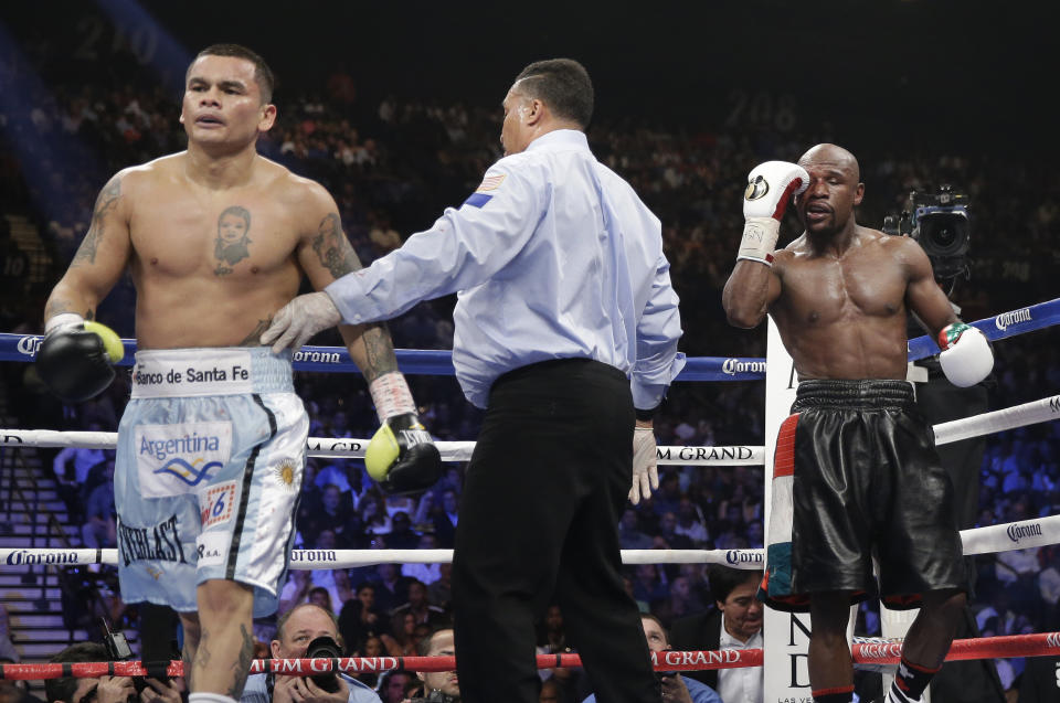 Marcos Maidana, left, is sent to his corner by referee Tony Weeks, center, after accidentally head butting Floyd Mayweather Jr. in their WBC-WBA welterweight title boxing fight Saturday, May 3, 2014, in Las Vegas. (AP Photo/Isaac Brekken)