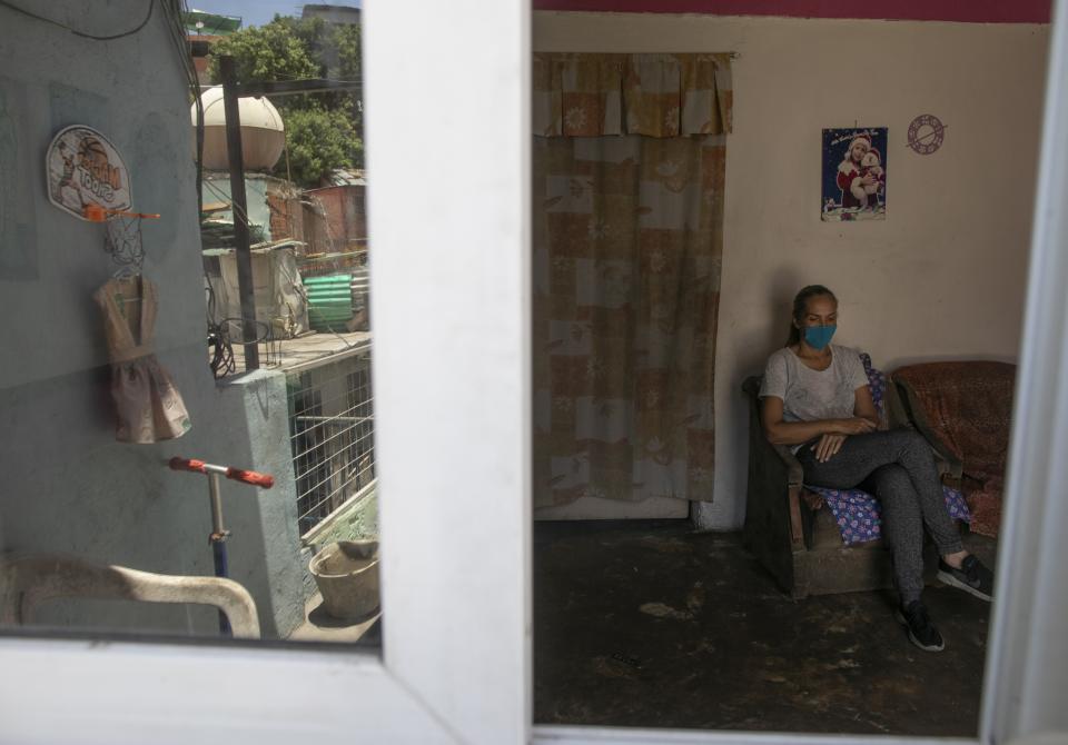 In this April 24, 2020 photo, Maylin Perez sits inside her three-room apartment in Caracas, Venezuela. Perez said she tries to convince her son who is working in Peru not to worry about sending money because she's more concerned about him potentially getting infected with the new coronavirus. (AP Photo/Ariana Cubillos)