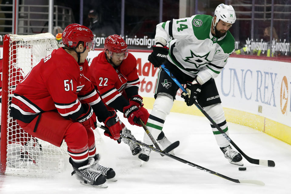 Dallas Stars' Jamie Benn (14) tries to protect the puck from Carolina Hurricanes' Brett Pesce (22) and Jake Gardiner (51) during the first period of an NHL hockey game in Raleigh, N.C., Sunday, Jan. 31, 2021. (AP Photo/Karl B DeBlaker)