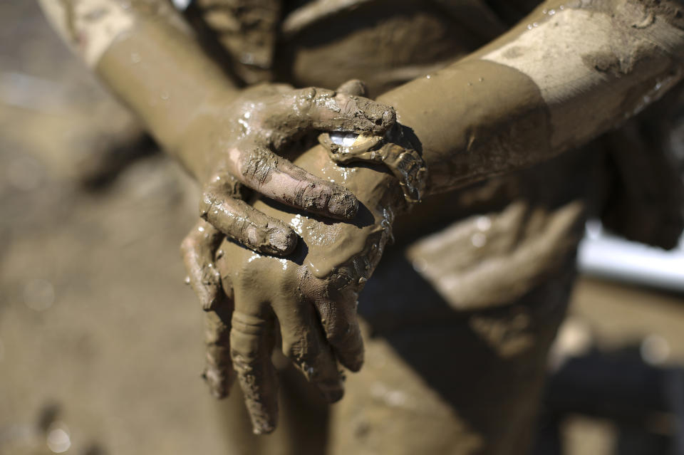 Gina Belchez wipes mud from her watch as she retrieves belongings from the typhoon-damaged Kasiglahan village in Rodriguez, Rizal province, Philippines on Friday, Nov. 13, 2020. Thick mud and debris coated many villages around the Philippine capital Friday after Typhoon Vamco caused extensive flooding that sent residents fleeing to their roofs and killing dozens of people. (AP Photo/Aaron Favila)