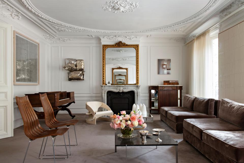 Directly to the left of the entrance is the main salon. The room is filled with an eclectic combination of vintage pieces, family heirlooms, and contemporary art. A coffee table by Danish designer Poul Kjaerholm, rosewood chairs by Norweigian designer Hans Brattrud, and a sculptural low armchair by Joe Colombo can all be seen. The series of sofas were based on an existing model and redesigned by architect Benoit Dupuis, who had them covered in a silk velvet from Edmond Petit. The artworks hanging are from left to right by Jurgen Drescher, Jim Lambie, Louise Lawler, and Latifa Echakhch. The piano came with the apartment. The floral arrangements were designed by Arturo Arita.