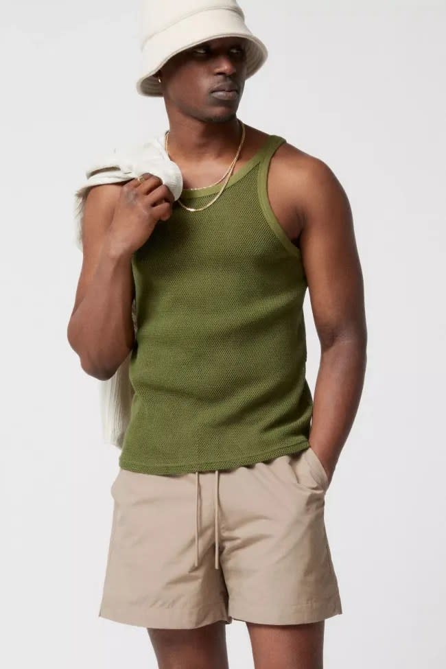 A person wearing a Urban Outfitters green mesh tank.