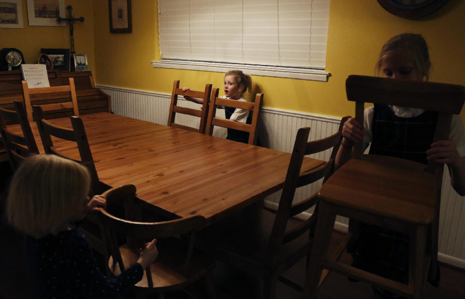 In this Feb. 7, 2020, photo, sisters, from left, Bernadette Whitfield, 4, Zoe-Catherine, 5, and Maggie, 9, choose seats around the dinner table at their home in north Dallas. (AP Photo/Jessie Wardarski)