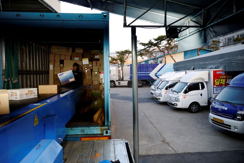 A worker loads parcels onto a conveyor belt from a delivery truck at a Hanjin Transportation distribution centre in Gwangju