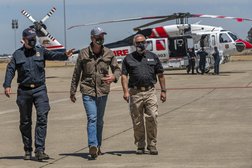 California Gov. Gavin Newsom, center, arrives at a press conference on a new Sikorsky S70i Black Hawk firefighting helicopter with Cal Fire chief Thomas Porter, left, and Mark Ghilarducci, director of the California Office of Emergency Services, right, to highlight new firefighting equipment and his proposed $2 billion investment in wildfire and emergency preparedness at a press conference in McClellan Park in Sacramento County on Monday, May 24, 2021. (Renee C. Byer/The Sacramento Bee via AP)