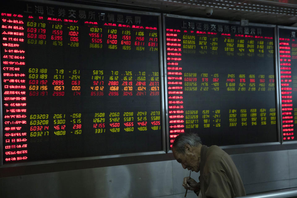 An investor eats a meal near a board displaying stock prices at a brokerage in Beijing Monday, Nov. 11, 2019. Shares declined Monday in Asia as investors watched for the latest developments in the China-U.S. trade war sage. (AP Photo/Ng Han Guan)