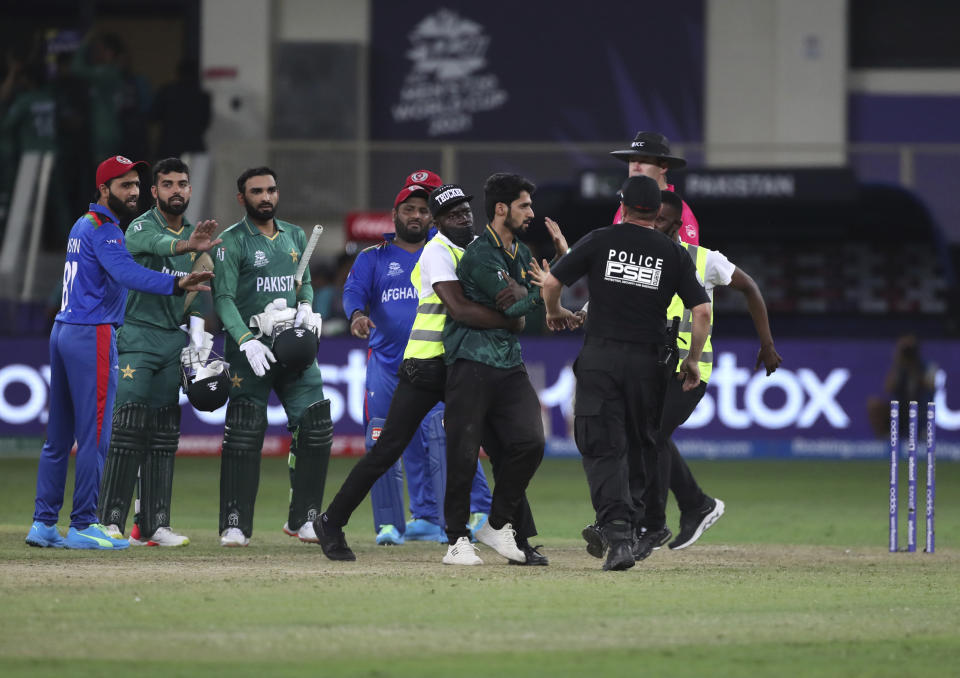 Pakistan and Afghanistan players react as a pitch invader is being taken away by security men after Pakistan won the Cricket Twenty20 World Cup match against Afghanistan in Dubai, UAE, Friday, Oct. 29, 2021. (AP Photo/Aijaz Rahi)