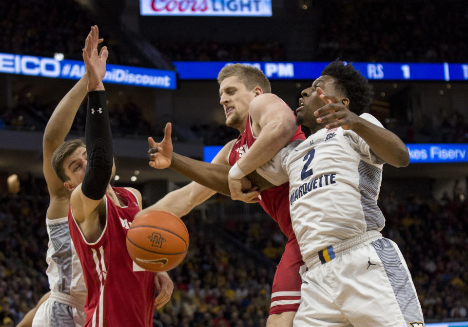 Wisconsin guard Brevin Pritzl, center, grabs a rebound from Marquette forward Sacar Anim, right, during the first half of an NCAA basketball game Saturday, Dec. 8, 2018, in Milwaukee. (AP Photo/Darren Hauck)