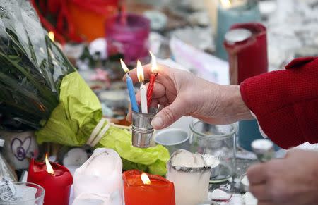 A woman installs blue, white and red candles, the colours of the French flag, during a tribute to the victims of Paris attacks, at the Place de la Republique in Paris, France, November 27, 2015 as the French President called on all French citizens to hang the tricolour national flag from their windows on Friday to pay tribute to the victims of the Paris attacks during a national day of homage. REUTERS/Eric Gaillard