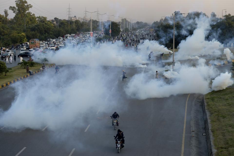 Supporters of former Prime Minister Imran Khan's party run for shelter after police fired tear gas shells to disperse them during a protest to condemn the election commission's decision, in Islamabad, Pakistan, Friday, Oct. 21, 2022. Pakistan’s elections commission on Friday disqualified former Prime Minister Imran Khan from holding public office for five years, after finding he had unlawfully sold state gifts and concealed assets as premier, officials said. (AP Photo)