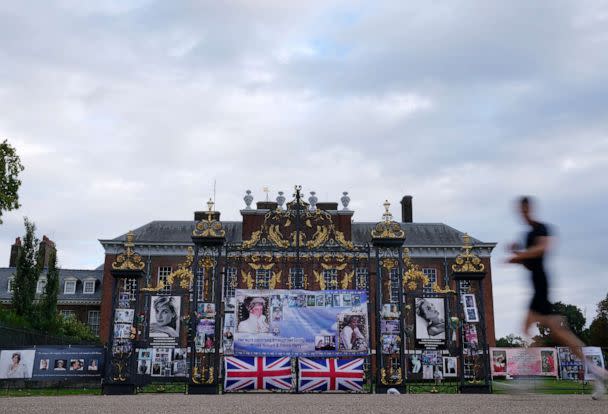 PHOTO: A man runs by portraits of Princess Diana displayed on the gates of Kensington Palace, in London, Aug. 30, 2022.  (Alastair Grant/AP)