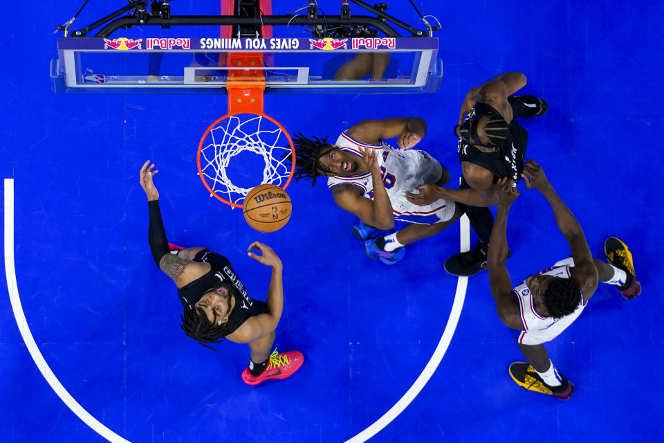 Tyrese Maxey de los 76ers de Filadelfia lanza el balón sobre Nicolas Claxton y Trendon Watford, de los Nets de Brooklyn en el encuentro de la NBA del domingo 14 de abril del 2024. (AP Foto/Chris Szagola)