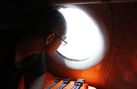 A Chinese journalist looks out from the window of a Vietnamese airforce AN-26 during a mission to find the missing Malaysia Airlines flight MH370 off Tho Chu islands March 11, 2014. REUTERS/Kham