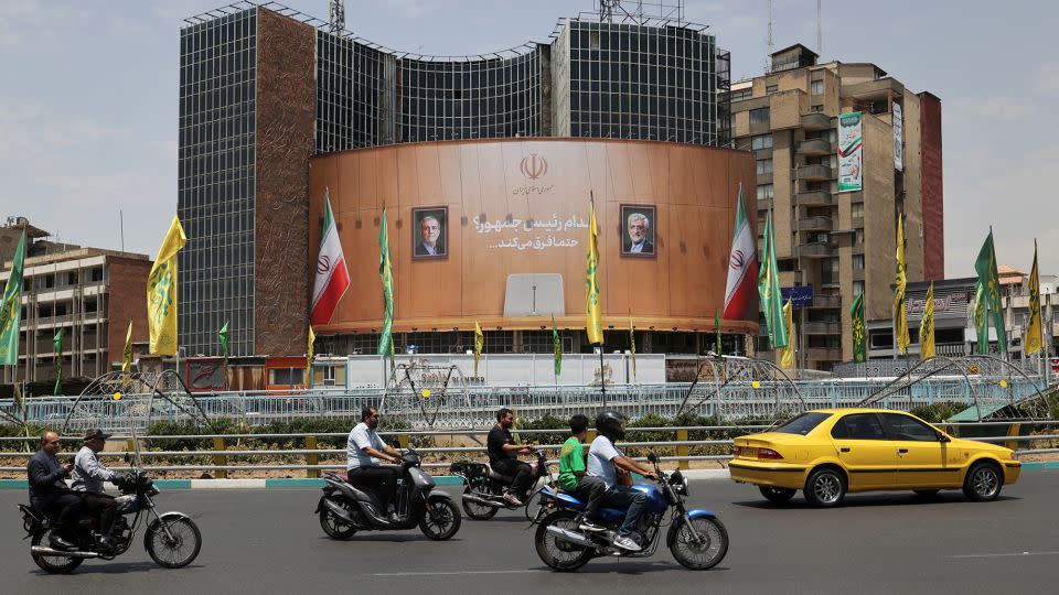 People drive past a billboard with pictures of presidential candidates Masoud Pezeshkian and Saeed Jalili on a street in Tehran, Iran, on Monday. - Majid Asgaripour/WANA/Reuters