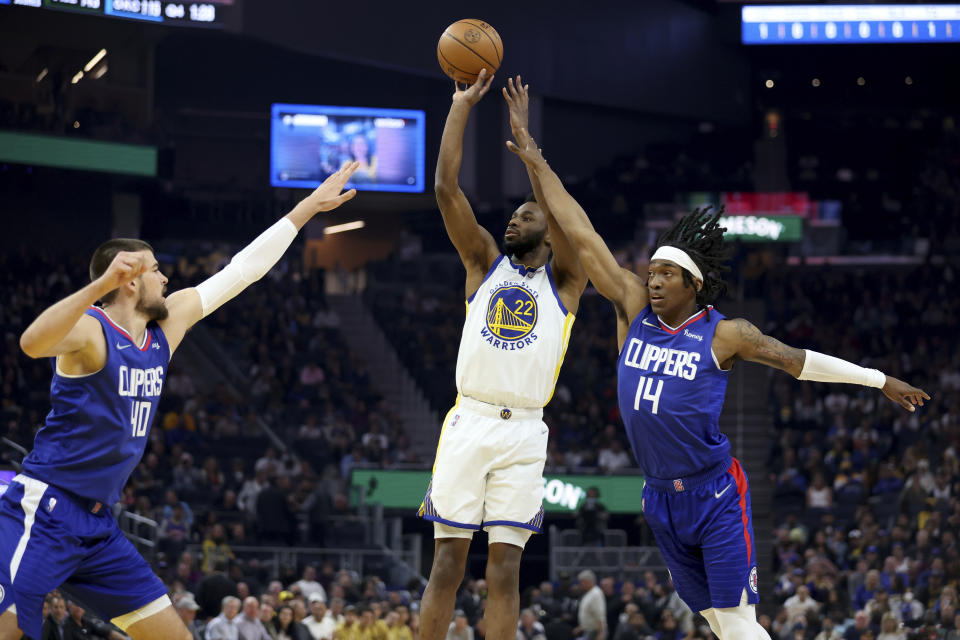 Golden State Warriors forward Andrew Wiggins (22) shoots from between Los Angeles Clippers center Ivica Zubac, left, and guard Terance Mann during the first half of an NBA basketball game in San Francisco, Tuesday, March 8, 2022. (AP Photo/Jed Jacobsohn)