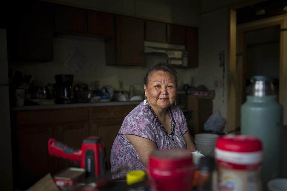 Vera Manutoli poses for a portrait inside her home, Sunday, Aug. 20, 2023, in Akiachak, Alaska. Vera originally obtained plumbing for her home in 2022, but resorted back to a bucket system after a pipe cracked during wintertime. The pipe has yet to be repaired. (AP Photo/Tom Brenner)