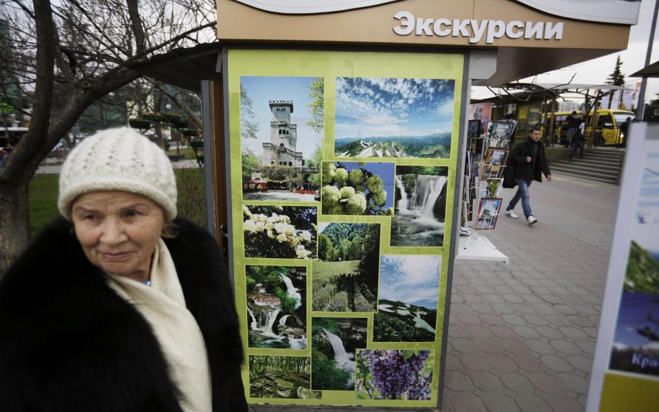 In this photo taken Monday, Feb. 10, 2014, scenic photos decorate the kiosk of 74-year-old Sochi native Dina Kobolenko, left, as she waits for tourists outside the central train station in Sochi, Russia. Vladimir Putin isn’t the only one who has a lot riding on the success of the Sochi Olympics. Local businesses and residents have a lot to gain if these Olympics fulfill Putin’s pledge to turn Sochi and its environs from a summer playground for well-off Russians into a year-round international resort for everyone. But that’s a big “if.” But for all the money spent on Olympic infrastructure, Kobolenko said, “This was a village, is a village and will remain a village," not Russia’s answer to Las Vegas or Dubai. (AP Photo/David Goldman)