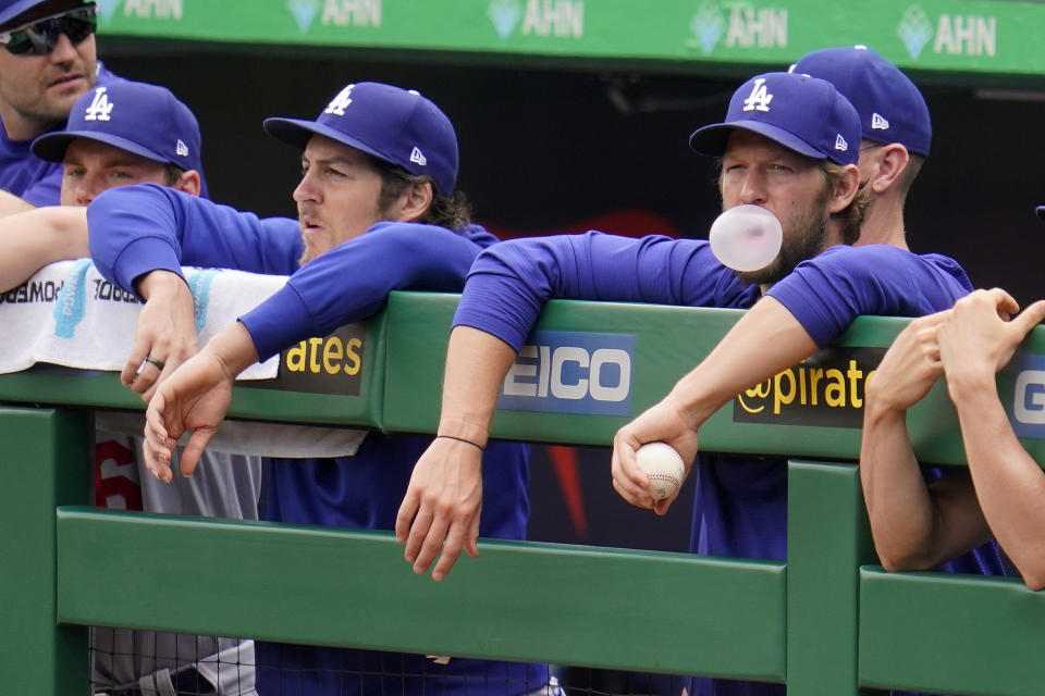 Los Angeles Dodgers' Clayton Kershaw, right, blows a bubble as he and Trevor Bauer, third from left, stand in the dugout during a baseball game against the Pittsburgh Pirates in Pittsburgh, Thursday, June 10, 2021. (AP Photo/Gene J. Puskar)