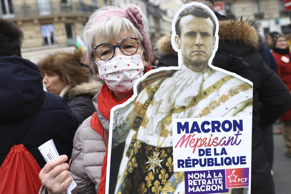 A demonstrator shows a poster of French President Emmanuel Macron as a king during a demonstration, Tuesday, March 7, 2023 in Paris. Demonstrators were marching across France on Tuesday in a new round of protests and strikes against the government's plan to raise the retirement age to 64, in what unions hope to be their biggest show of force against the proposal. (AP Photo/Aurelien Morissard)