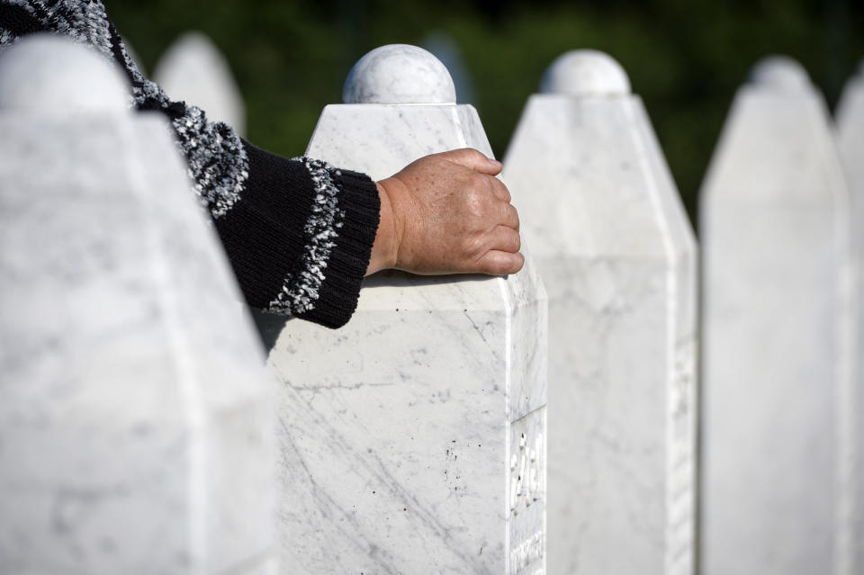 A woman touches a grave stone in Potocari, near Srebrenica, Bosnia, Saturday, July 11, 2020. Nine newly found and identified men and boys were laid to rest as Bosnians commemorate 25 years since more than 8,000 Bosnian Muslims perished in 10 days of slaughter, after Srebrenica was overrun by Bosnian Serb forces during the closing months of the country's 1992-95 fratricidal war, in Europe's worst post-WWII massacre. (AP Photo/Kemal Softic)