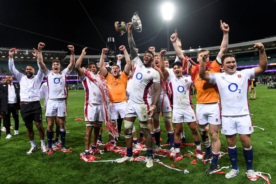 Pictured centre, England captain Courtney Lawes holds the trophy aloft as he celebrates a series victory against the Wallabies with teammates. 