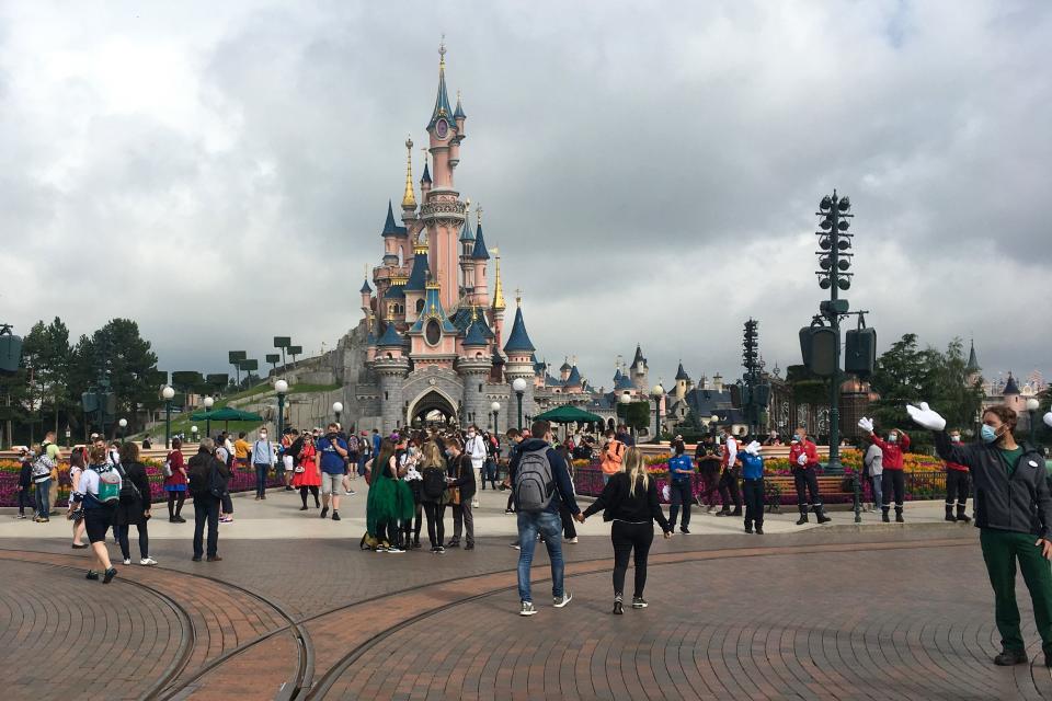 Visitors and staff wearing protective face masks, walk down the Main Street of Disneyland Paris in Marne-la-Vallee, near Paris, on July 15, 2020, as Disneyland Paris begins phased reopening after months-closure aimed at stemming the spread of the novel coronavirus (COVID-19). (Photo by Aurelia MOUSSLY / AFP) (Photo by AURELIA MOUSSLY/AFP via Getty Images)