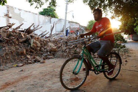 A man rides his bicycle past houses damaged in an earthquake that struck the southern coast of Mexico late on Thursday, in Juchitan, Mexico, September 9, 2017. REUTERS/Carlos Jasso