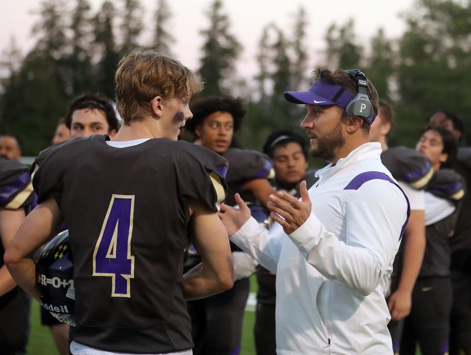 North Kitsap assistant coach Chris Richardson talks with Morgan Paul on the sidelines as the team prepares to take the field against Bainbridge, in Poulsbo on Friday, Sept. 30, 2022. 