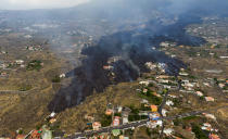 Lava from a volcano eruption flows destroying houses on the island of La Palma in the Canaries, Spain, Tuesday, Sept. 21, 2021. A dormant volcano on a small Spanish island in the Atlantic Ocean erupted on Sunday, forcing the evacuation of thousands of people. Huge plumes of black-and-white smoke shot out from a volcanic ridge where scientists had been monitoring the accumulation of molten lava below the surface. (AP Photo/Emilio Morenatti)