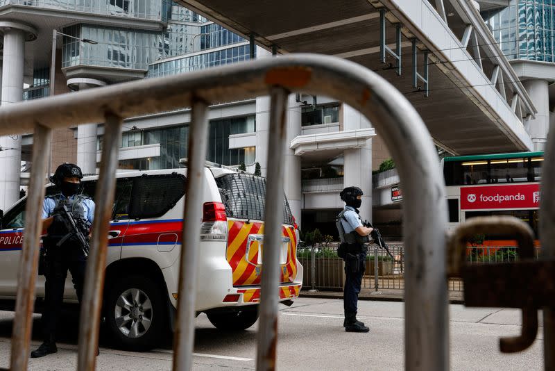 Armed police stand guard as they escort a prison van that is believed to carry media mogul Jimmy Lai, founder of Apple Daily, to the High Court in Hong Kong