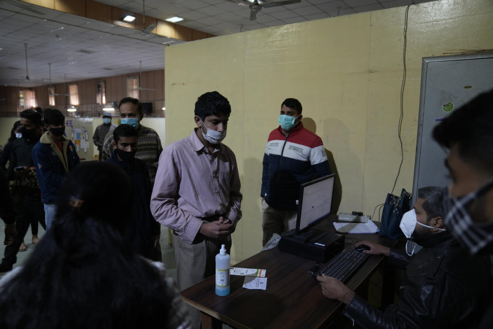 People wait in a queue to register for a Covid-19 vaccination at a makeshift center in a government school in New Delhi, India, Friday, Jan. 28, 2022. Indian health officials said that the first signs of COVID-19 infections plateauing in some parts of the vast country were being seen, but cautioned that cases were still surging in some states. (AP Photo/Manish Swarup)