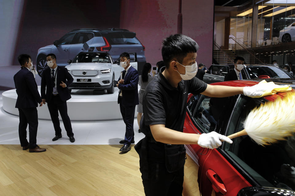 Staff members wearing face masks to help curb the spread of the coronavirus gather near the Volvo car models on display at the Auto China 2020 show in Beijing, Sunday, Sept. 27, 2020. Auto China 2020, postponed from March, is the first major trade show for any industry since the pandemic began as automakers are looking to China, the first major economy to start recovering from the coronavirus pandemic, to drive sales growth and reverse multibillion-dollar losses. (AP Photo/Andy Wong)