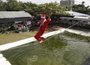 Jonald Libres, 28, walks on a tight rope over live crocodiles while wearing a Santa Claus costume as part of performances for the Christmas Yuletide season at a crocodile farm in Pasay city, metro Manila December 12, 2013. REUTERS/Romeo Ranoco (PHILIPPINES - Tags: SOCIETY ANIMALS)