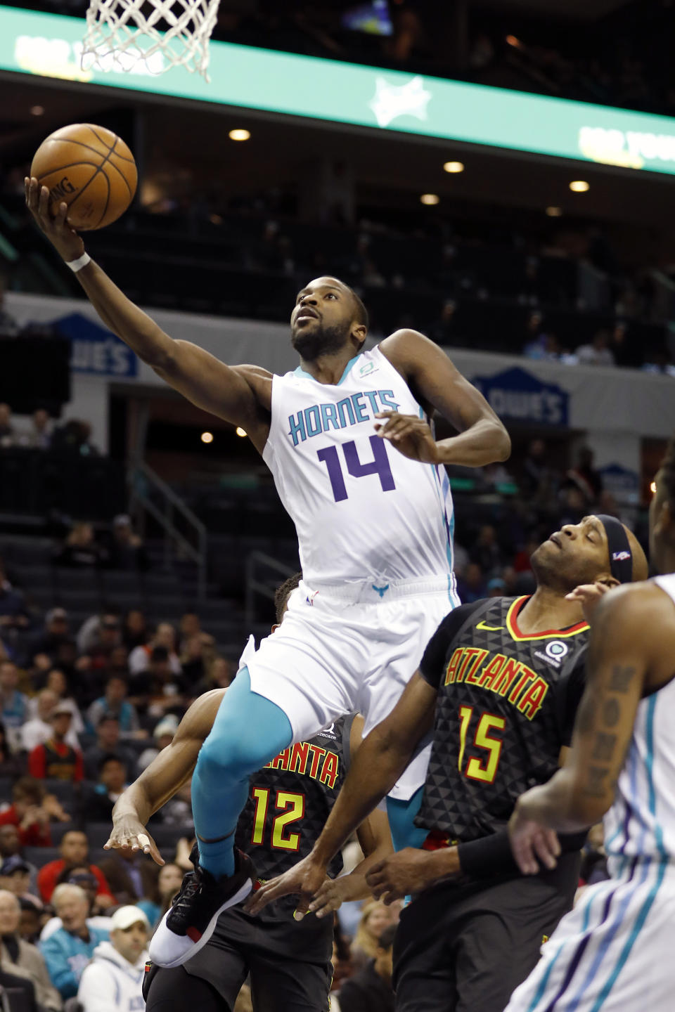 Charlotte Hornets' Michael Kidd-Gilchrist (14) gets his shot off as he drives by Atlanta Hawks' Vince Carter (15) during the first half of an NBA basketball game in Charlotte, N.C., Sunday, Dec. 8, 2019. (AP Photo/Bob Leverone)