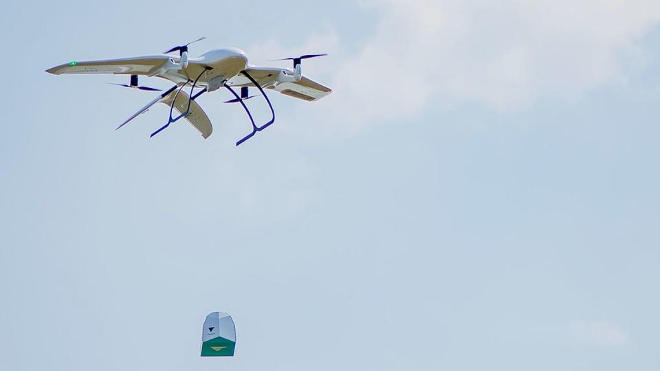 Eine Drohne des Start-Ups Wingcopter trägt ein Paket. Das mit Tragflächen ausgestattete Gerät kann senkrecht aufsteigen und dann auf der Strecke auch bei widrigen Wetterverhältnissen wie ein Propeller-Flugzeug fliegen.