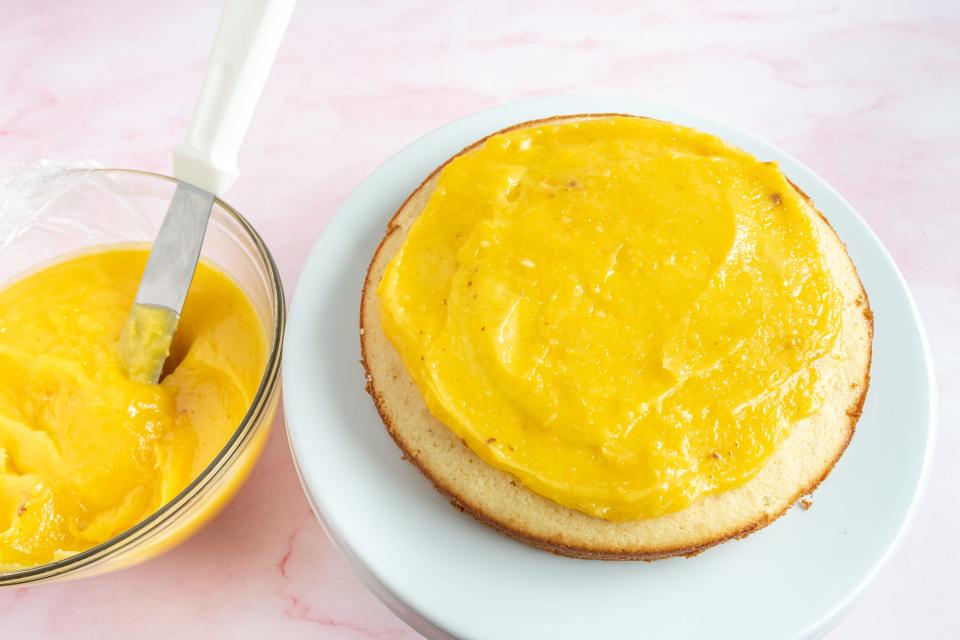 a round yellow cake with an orange filing spread on it
