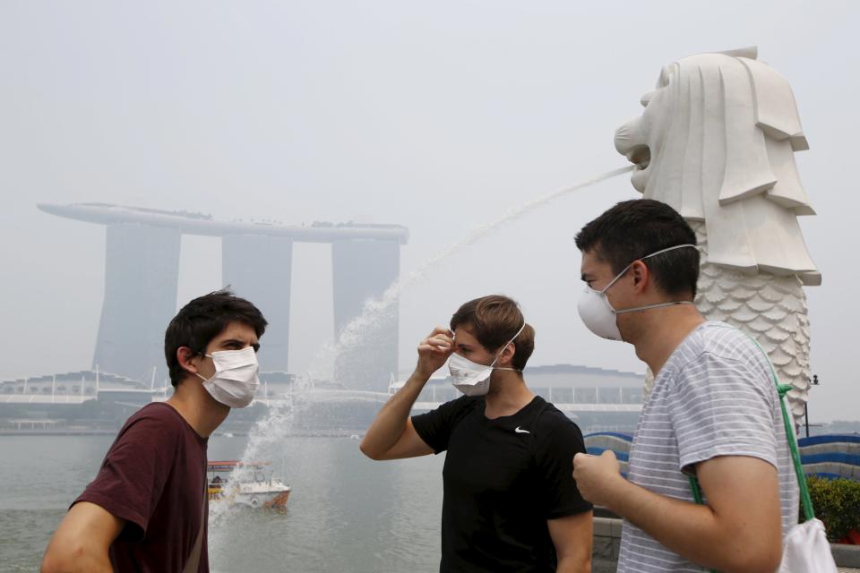 Tourists wearing masks visit the Merlion Park shrouded by haze in Singapore