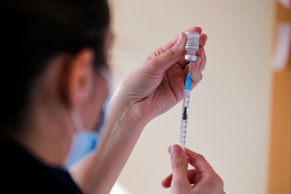 A person fills a syringe with the Pfizer vaccine. 