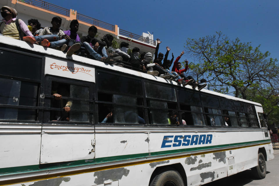 \LUCKNOW, INDIA - MARCH 29: Migrant workers react from on top of a bus as they make their return home on Day 5 of the 21 day nationwide lockdown imposed by PM Narendra Modi to curb the spread of coronavirus, at Asti Road, Bakshi Ka Talab, on March 29, 2020 in Lucknow, India. (Photo by Dheeraj Dhawan/Hindustan Times via Getty Images)